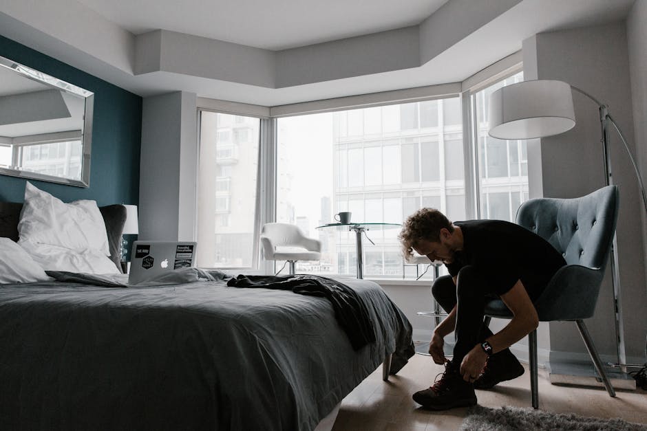 Contemporary hotel room with a man tying shoes in a bright Toronto setting.